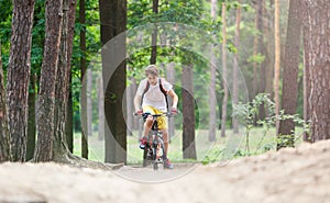 Child teenager in white t shirt and yellow shorts on bicycle ride in forest at spring or summer. Happy smiling Boy cycling outdoor