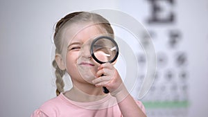 Child testing vision with magnifier, diagnosis of cornea, eyesight illness