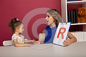 Child with therapist working on pronunciation and sounds together sitting in the class.