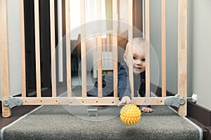 child throwing ball away through safety gates in front of stairs