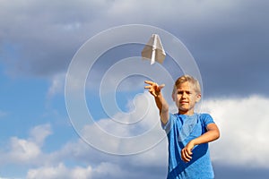 Boy throwing paper plane against blue sky