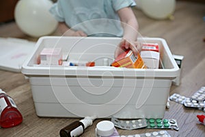 The child throws medicine from the first-aid kit. Unattended child. The child is played with drugs while the parents are not at ho
