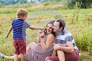 Child tickles his pregnant mother a blade of grass