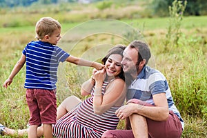 Child tickles his pregnant mother a blade of grass