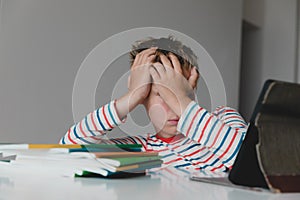 Child tired and bored of doing homework, kid stressed from learning indoors