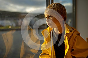 Child toddler boy on a ferry on a fjord, sunset on the deck of ferry on sunny day