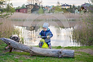 Child toddler near lake with bike actively playing