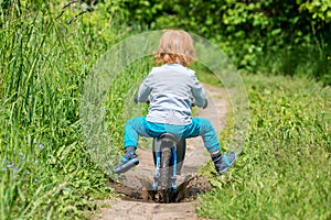 child toddler in summer meadow with bike  funny ride