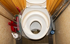 A child toilet seat on the toilet.An old dirty toilet.Toilet bowl with a small hole for coping needs.