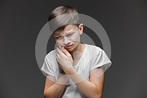 Child toothache. holding his cheek, dental pain. Closeup portrait boy with sensitive tooth. isolated grey wall background.