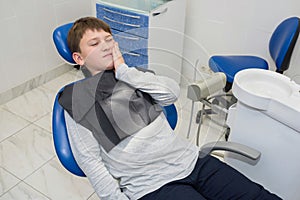 A child with a toothache is sitting at the dentistÃ¢â¬â¢s photo