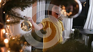 Child touches a ball on a christmas tree