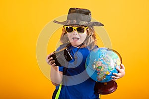 Child tourists with backpacks and camera hold world globe isolated on yellow background. Adventure, travel, and tourism