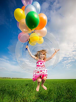 Child with toy balloons in spring field