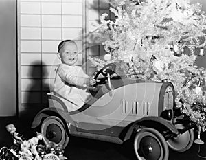 Child with toy car under Christmas tree