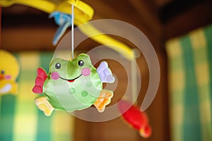 Child toy with frog hanging on baby cradle