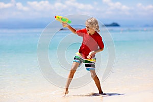 Child with toy water gun. Kids vacation beach fun