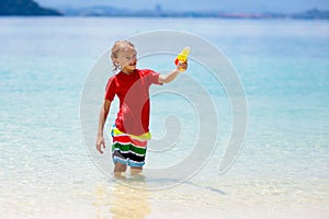 Child with toy water gun. Kids vacation beach fun