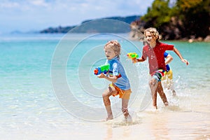 Child with toy water gun. Kids vacation beach fun