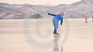 The child train on ice professional speed skating. The girl skates in the winter in sportswear, sport glasses, suit