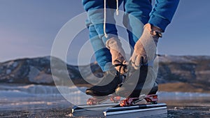 The child train on ice speed skating. Athlete puts on skates. The girl skates in the winter in sportswear, sport glasses