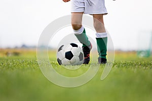 Child training soccer on fresh grass pitch. Low angle close-up image of soccer training