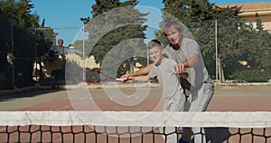 Child traning in tennis. Father and son practice blows in tennis on coart. Active leisure together.