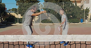 Child traning in tennis. Father and son practice blows in tennis on coart. Active leisure together.