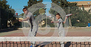 Child traning in tennis. Father and son practice blows in tennis on coart. Active leisure together.