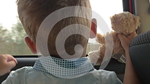 Child traveling in car with favourite teddy bear