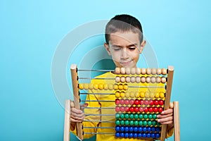 Child tries to solve mathematical problem with abacus. Cyan background