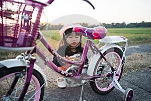 Child try to fix her own bicycle outdoor