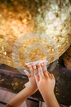 A child is trying to paste a gold sheet on round stones buried