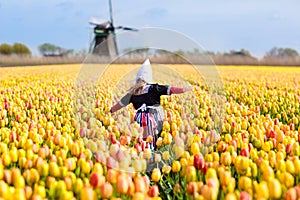 Child in tulip flower field. Windmill in Holland.