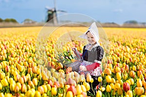 Child in tulip flower field. Windmill in Holland