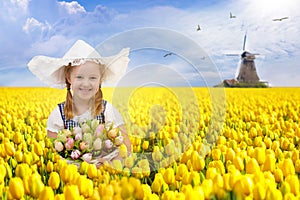 Child in tulip flower field. Windmill in Holland