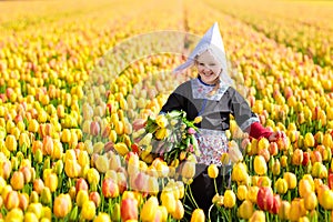 Child in tulip flower field. Windmill in Holland.