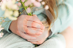 a child in a turquoise suit holds flowers in his hands, the focus is on his hands