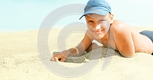 Child tween happy smiling, laying on sand at beach