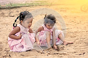 Child two asian little girls playing with sand in playground
