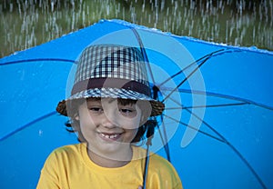 Child with an umbrella walks in the rain, happy boy with umbrella outdoors