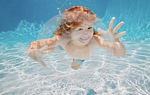 Child underwater. Funny face portrait of child boy swimming and diving underwater with fun in pool.