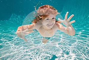 Child underwater. Funny face portrait of child boy swimming and diving underwater with fun in pool.