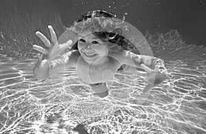 Child underwater. Funny face portrait of child boy swimming and diving underwater with fun in pool.