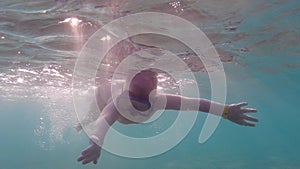 A child in an underwater mask learns to swim and dive. The boy dives into the sea