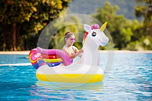 Child on unicorn float in swimming pool. Kids swim