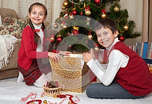 Child unpack gift boxes near christmas tree, decoration at home, happy emotion, winter holiday concept