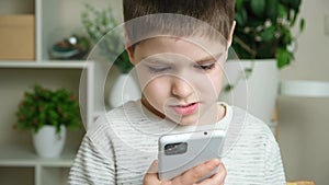 The child uses the phone, holds the smartphone in his hand and looks at the screen. Screen Time, Parental Controls