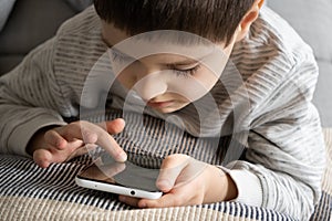 The child uses the phone, holds the smartphone in his hand and looks at the screen. Screen Time, Parental Controls