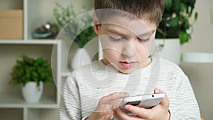 The child uses the phone, holds the smartphone in his hand and looks at the screen. Screen Time, Parental Controls